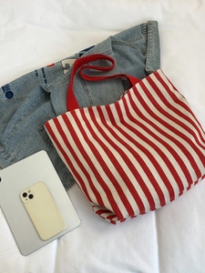 Flat lay of red and white striped canvas tote bag with tablet and denim jacket