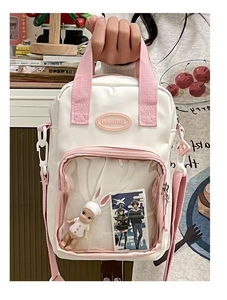 Close-up of beige crossbody ita bag with clear window showing plush doll and pink straps