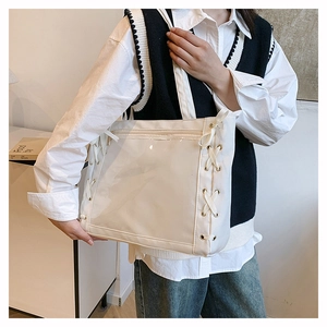 Detailed view of white canvas tote bag with transparent PVC pocket and ribbon lace-up details