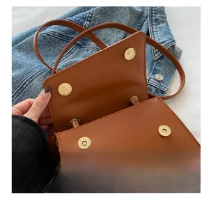 Close-up of golden metal magnetic buckle on vintage brown leather handbag with denim background