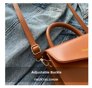 Close-up of adjustable metal buckle and smooth brown leather texture on handbag