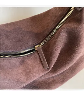 Dettaglio della cerniera in metallo dorato sulla borsa tote in pelle scamosciata marrone scuro