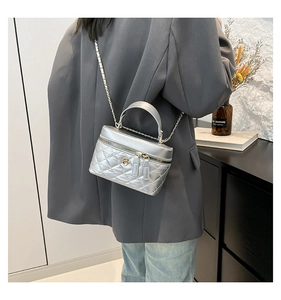 Detail of silver quilted bag showing metallic texture, chain strap, and gold flower charm