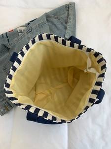 Macro view showing high-capacity interior of blue striped canvas tote bag with yellow lining
