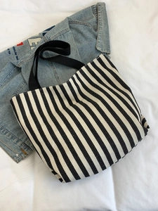 Close-up of black and white striped canvas tote bag with durable fabric handles on denim