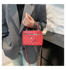 Detail of red quilted mini bag featuring flower metal charm and woven chain strap