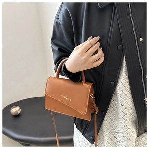 Detailed view of brown leather bag with slanted flap and Fashion & Bags inscription