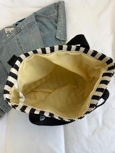 Detail view of striped canvas tote bag with bright yellow lining and zipper closure