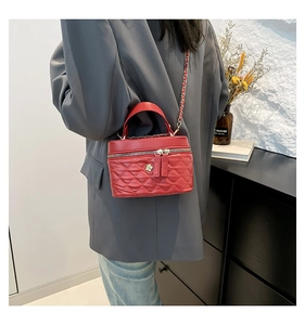 Red quilted leather bag with chain strap and gold flower detail worn with grey blazer