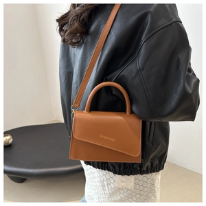 Side view of a brown vintage crossbody bag with asymmetric flap and fashion logo text