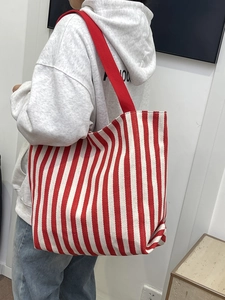 Detail showing red and white striped canvas tote bag with woven shoulder straps