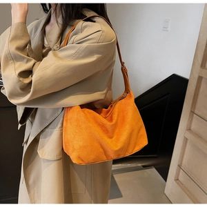 Dettaglio di una borsa hobo in pelle scamosciata arancione indossata a tracolla