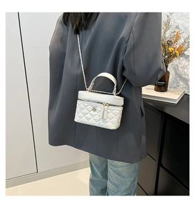 Detailed side view of a white quilted crossbody bag with a gold camellia floral clasp