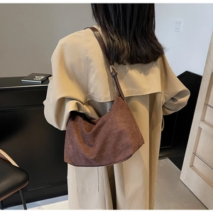 Dettaglio della borsa tote a mezzaluna in camoscio marrone scuro indossata da modella