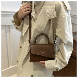 Detailed view of brown leather bag with gold Fashion & Bags lettering and top handle