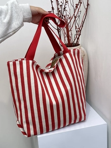 Close-up of durable red and white striped canvas tote bag with thick red fabric handles