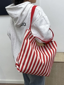 Detailed back view of a red striped large canvas tote bag carried by a model