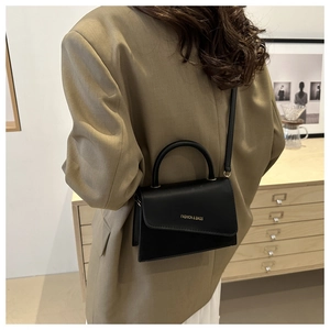 Modern black crossbody bag shown on model in a stylish interior lifestyle setting
