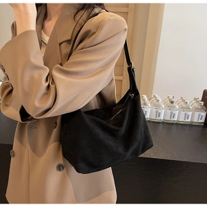 Dettaglio di una borsa tote in pelle scamosciata nera con tracolla abbinata a un blazer kaki