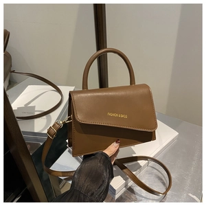 Detailed view of a brown leather crossbody bag featuring gold hardware and logo embossing