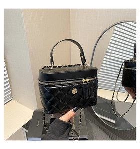 Close-up of quilted black leather handbag with white camellia flower and gold chain strap