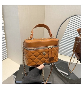 Detailed shot of brown quilted leather handbag with gold flower clasp and chain strap