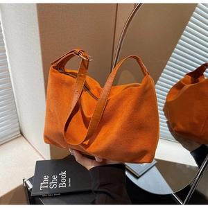 Dettaglio della borsa tote in pelle scamosciata arancione con tracolla e fibbia d'oro