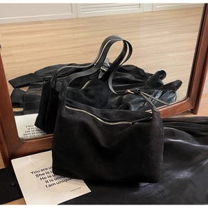 Dettaglio della borsa tote in pelle scamosciata nera opaca con cerniera in metallo e fibbia