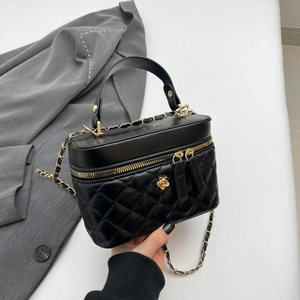 Quilted black handbag with golden camellia detail and chain strap on wool coat