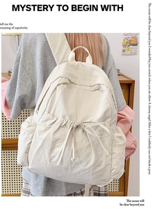Detailed view of cream nylon backpack featuring drawstring closure and side zipper pocket