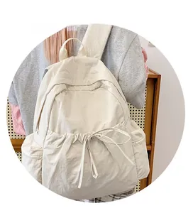 Detailed view of cream nylon backpack featuring drawstring closure and side zipper pockets