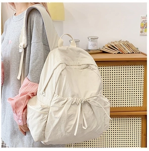 Detail view of off-white backpack featuring drawstring fold design and smooth side pocket