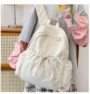 Detailed view of cream nylon backpack with drawstring and adjustable wide straps for commuting