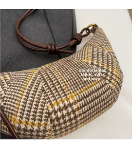 Detailed view of the soft plaid textured fabric and knotted leather strap on this crescent bag