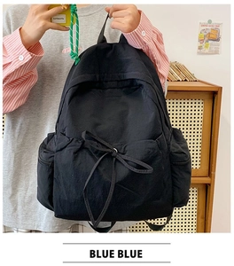 Detail of minimalist black nylon backpack featuring waterproof texture and decorative bow
