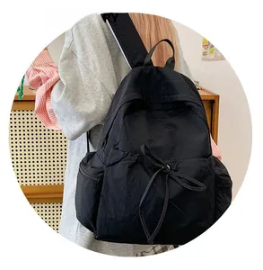 Detail view of large black canvas backpack featuring a drawstring front pocket and side storage