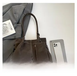 Detail of dark brown tote bag with white contrast stitching and a small matching pouch