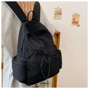 Detailed view of the black nylon backpack showing drawstring pocket and padded shoulder straps