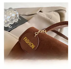 Vue détaillée d'un sac à main en daim marron avec boucle dorée et pendentif chic