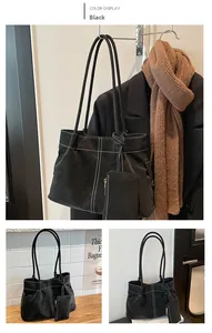 Detail view of black faux suede tote bag with bold white stitching and mini pouch accessory
