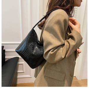 Detail of black faux crocodile skin texture on a vintage style shoulder bag