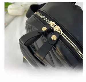 Close-up of golden dual zippers and V-quilted texture on a black mini backpack