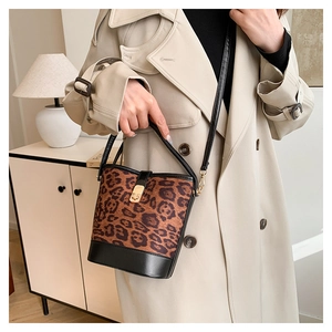 Detail of leopard print bucket bag with black leather base and gold twist-lock closure