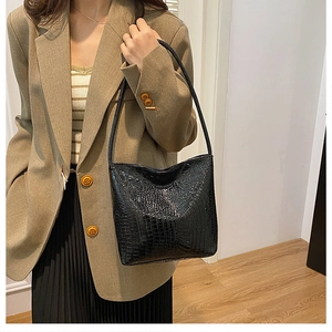 Close-up of black crocodile embossed shoulder bag worn with casual chic blazer