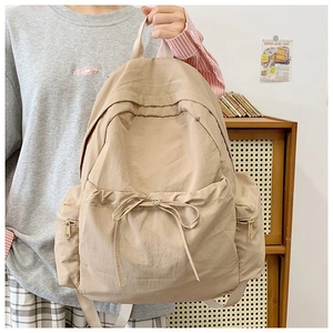 Detail of khaki backpack featuring drawstring bow decoration and side zipper pockets