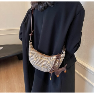 Detail of crossbody moon bag in brown houndstooth fabric with dog charm on black coat