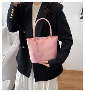 Pink nylon mini tote bag with heart pendant shown carried by model in casual outfit