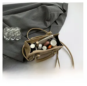 Detail view showing the spacious interior of khaki crossbody bag with smartphone and makeup