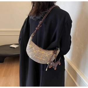 Detail of crescent canvas bag with houndstooth pattern and dachshund charm on shoulder