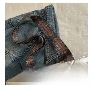 Détail d'un sac cabas matelassé blanc avec une bandoulière tissée colorée style bohème